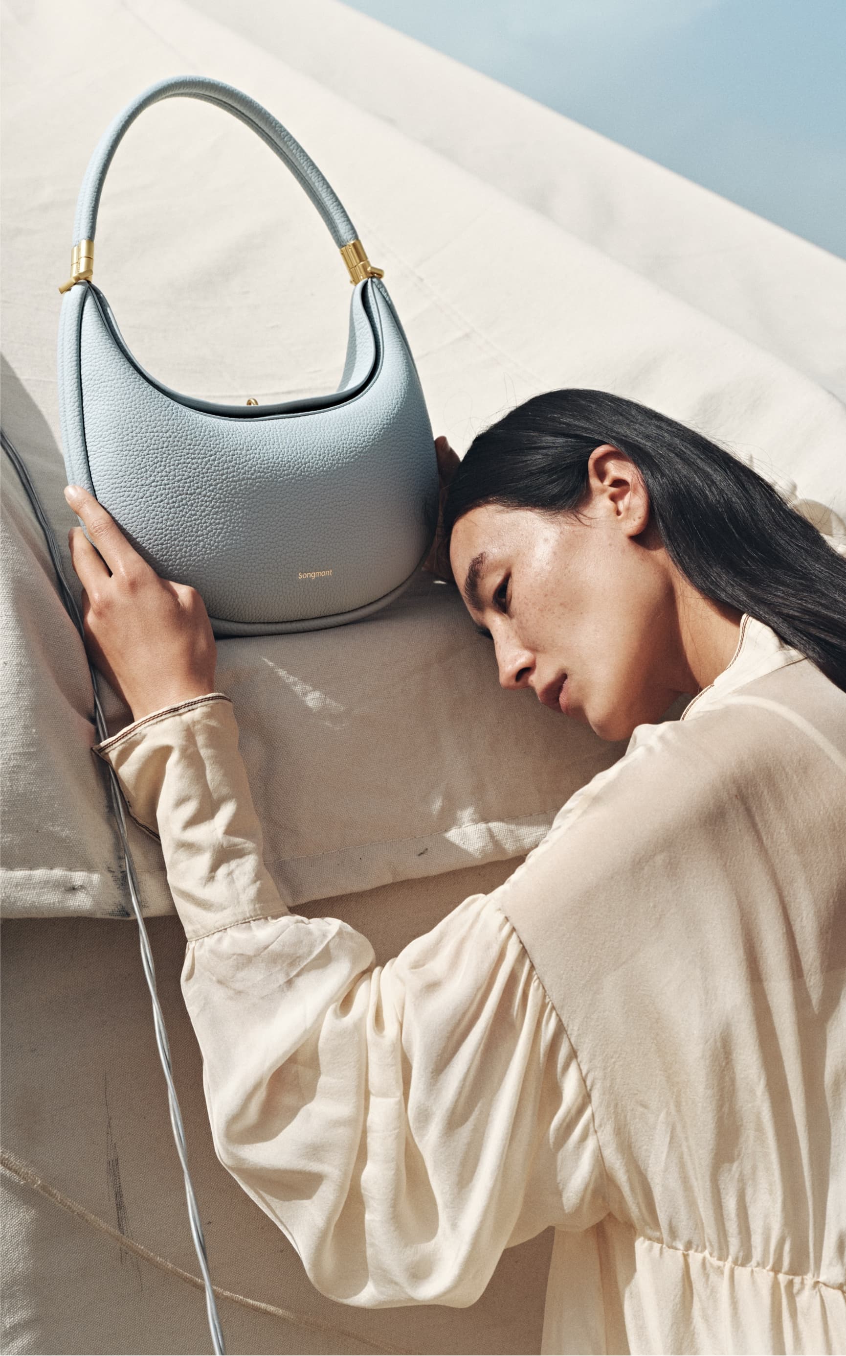 Woman holding a light blue handbag with a blurred background