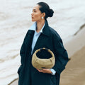 Medium Luna Hobo Bag in Dune Suede held by a woman on a beach