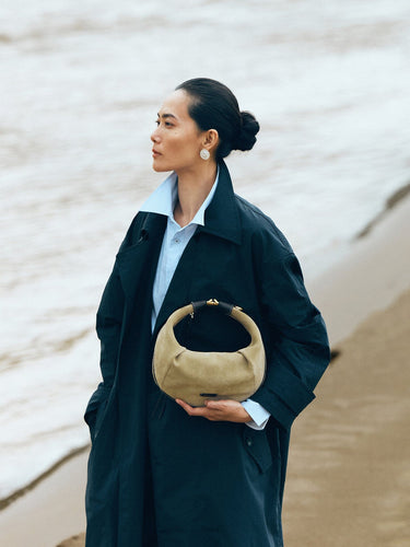 Medium Luna Hobo Bag in Dune Suede held by a woman on a beach