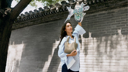 Woman holding a handbag and a decorative item against a traditional architectural background