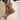 Songmont Puppy Charm accessory in tan and brown leather with white stitching on a beige handbag.