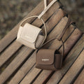 Songmont full-grain leather AirPods cases in beige and brown with flap closure and embossed logo