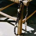 Large Carefree Thread Charm Sandal: dark beads, leather diamonds, seed beads on wooden stool.