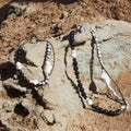 Large Carefree Thread Charm in Sandal color, featuring sandalwood, seed beads, and leather diamonds on a rocky surface.