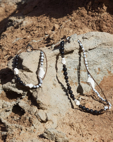 Large Carefree Thread Charm in Sandal color, featuring sandalwood, seed beads, and leather diamonds on a rocky surface.