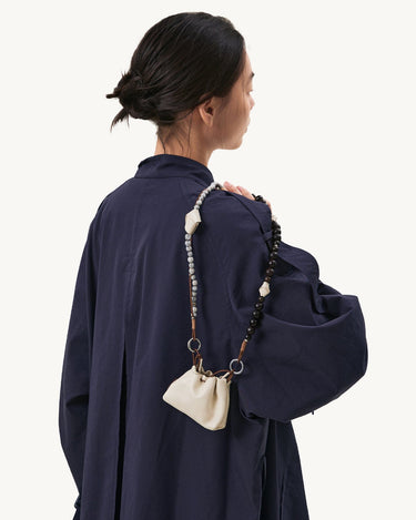 Large Carefree Thread Charm in Sandal color, featuring sandalwood and seed beads, with a cream leather pouch.