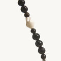 Small Carefree Thread Charm with alternating dark wooden and natural beads, featuring a white leather knot detail.