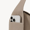 Drippy Roof Bag in Cobble leather, showing a phone pocket with a smartphone partially inserted.