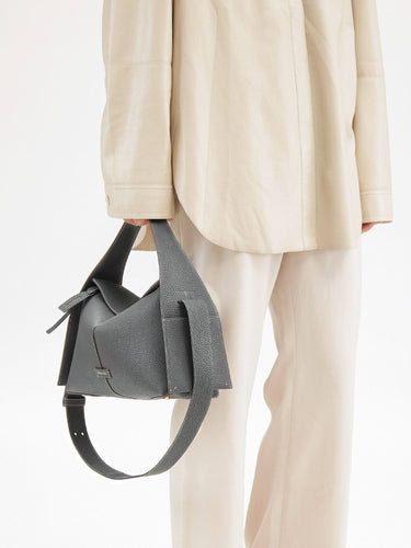 Drippy Roof Bag in stardust grey textured leather, styled with an oversized beige shirt and trousers.