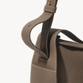 Drippy Roof Bag in taupe full-grain leather with white contrast stitching and adjustable strap.