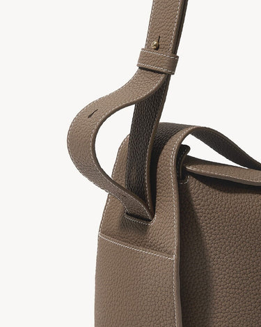 Drippy Roof Bag in taupe full-grain leather with white contrast stitching and adjustable strap.