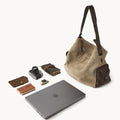 Extra Large Yore Hobo Bag in dune suede and coffee leather, shown with a laptop, camera, notebook, and smartwatch.