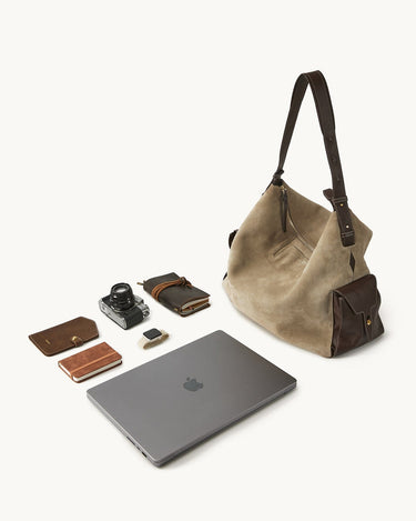 Extra Large Yore Hobo Bag in dune suede and coffee leather, shown with a laptop, camera, notebook, and smartwatch.