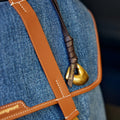 Close-up of Faith Stone Charm in onyx denim with tan leather strap and gold hardware, featuring "Songmont" logo.