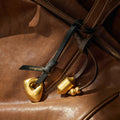 Faith Stone Charm in onyx, gold stone pendant and cylindrical charm on leather straps with Songmont logo.