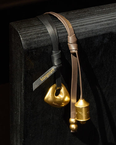 Faith Stone Charm & Prayer Wheel Charm Set in Sandal and Onyx colors, featuring gold-toned pendants.