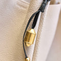 Faith Stone charm detail with brass prayer wheel, engraved patterns, and gold beads on leather strap.