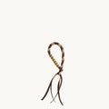 Freedom Cord accessory with braided leather loop, gold beads, and leather tassels in Sandal Camel color.