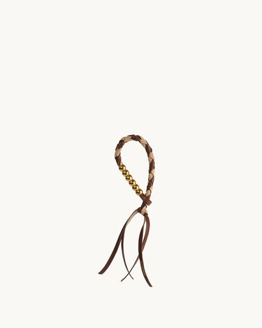 Freedom Cord accessory with braided leather loop, gold beads, and leather tassels in Sandal Camel color.