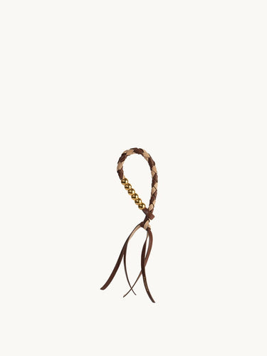 Freedom Cord accessory with braided leather loop, gold beads, and leather tassels in Sandal Camel color.