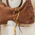 Brown suede Freedom Cord bag with braided leather detail and gold beads.