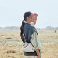 Gather Clutch Set in Cloud: Cream Nappa leather bag with beaded strap, worn by a woman in an outdoor setting.