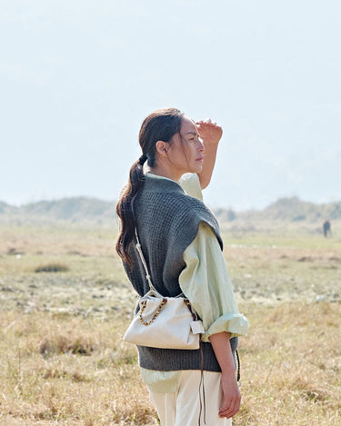 Gather Clutch Set in Cloud: Cream Nappa leather bag with beaded strap, worn by a woman in an outdoor setting.