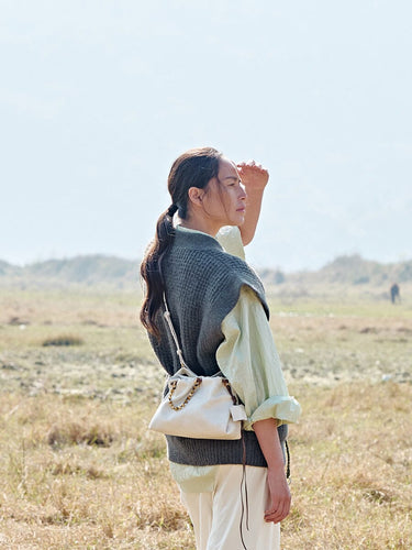 Gather Clutch Set in Cloud: Cream Nappa leather bag with beaded strap, worn by a woman in an outdoor setting.