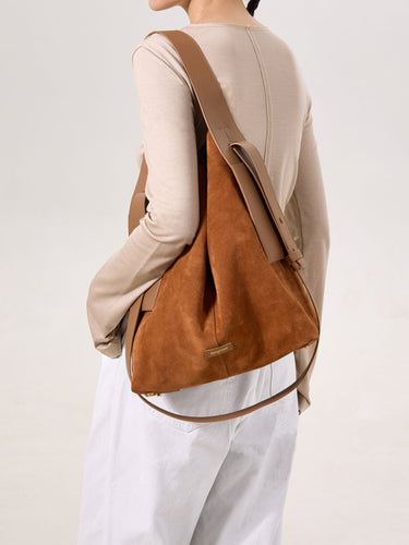 Caramel colored large suede tote bag worn by a model on the shoulder, featuring leather straps and a subtle brand logo.