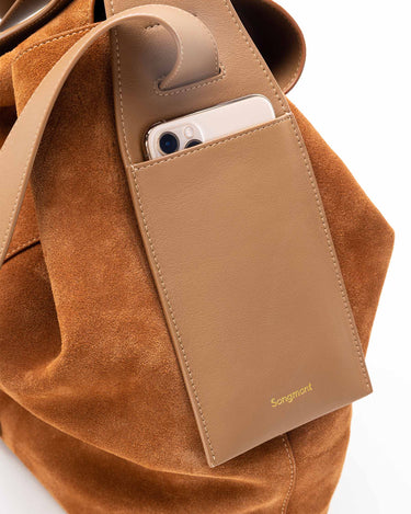 Caramel suede Large Drippy Tote Bag with leather phone pocket holding a smartphone. Gold Songmont logo.