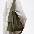 Olive suede large Drippy tote bag with leather strap and "Songmont" logo, worn by a person in a beige trench coat.