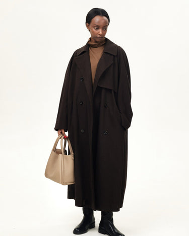 Large Song Bag in Cream Apricot, a textured leather tote carried by a woman in a dark brown trench coat.