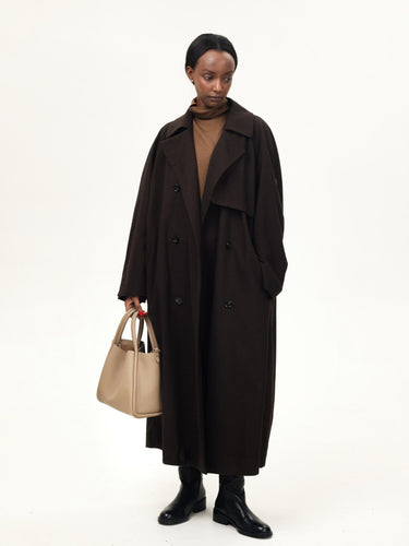 Large Song Bag in Cream Apricot, a textured leather tote carried by a woman in a dark brown trench coat.