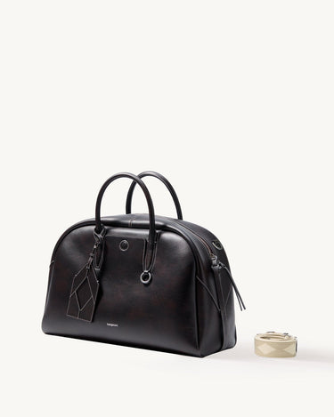 Dark brown Yore bowling bag in full-grain Nappa leather with white stitching and top handles. Includes a detachable patterned strap.