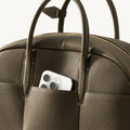 Moss green Yore bowling bag with a smartphone in the front pocket and brass zipper.