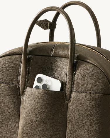 Moss green Yore bowling bag with a smartphone in the front pocket and brass zipper.