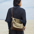 Large Yore Hobo Bag in Dune Suede with leather accents, worn by a person against a desert backdrop.