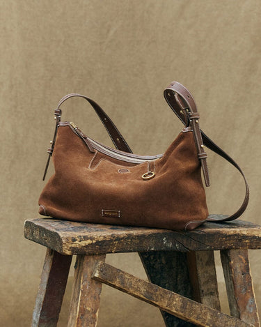 Large Yore Hobo Bag in sandal suede on wooden stool, featuring adjustable strap and 'songmont' logo.