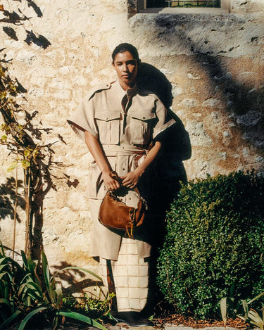 Woman in safari outfit holding a brown suede large Yore Hobo Bag with fringed detail.