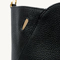 Close-up of the textured black leather of the Large Yore Tote Bag, showing a golden ring detail and a subtle cutout.