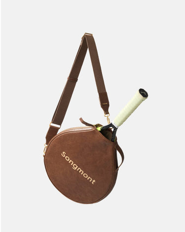 Brown Songmont leather tennis racket cover with adjustable strap, carrying a tennis racket.