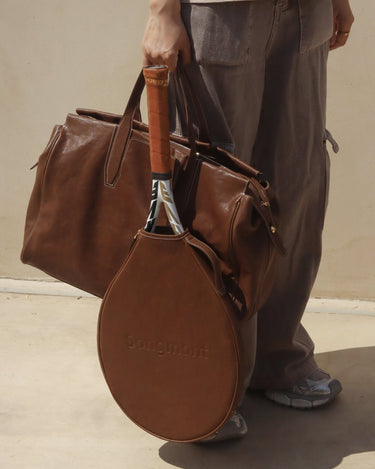 Limited edition brown leather tennis racket cover with embossed 'Songmont' logo, paired with a matching duffel bag.