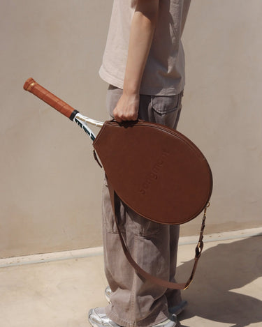 Brown vegetable-tanned leather tennis racket cover with embossed "Songmont" logo, holding a tennis racket.