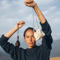 Woman holding a dark brown and an off-white full-grain nappa leather Lucky Pouch Charm with adjustable straps.