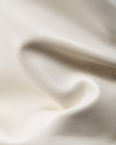 Creamy white full-grain Nappa leather texture, showing supple folds and a subtle pebbled grain.