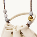 Cream full-grain nappa leather pouch charm with adjustable strap, featuring grey and gold bead accents.