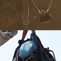 Lucky Pouch Charm in dark grey fabric with leather strap and a small denim accessory.