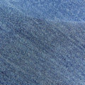 Close-up texture of blue denim fabric, showcasing the characteristic diagonal weave and subtle color variations of the Lucky Pouch Charm.