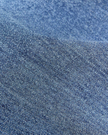 Close-up texture of blue denim fabric, showcasing the characteristic diagonal weave and subtle color variations of the Lucky Pouch Charm.