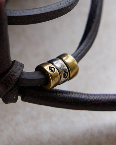 Lucky Pouch Charm: Leather strap with gold and silver beads, featuring etched designs.